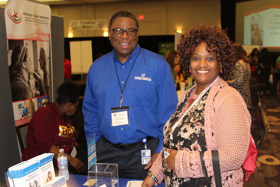 Lady and gentlemen standing at exhibit booth at conference